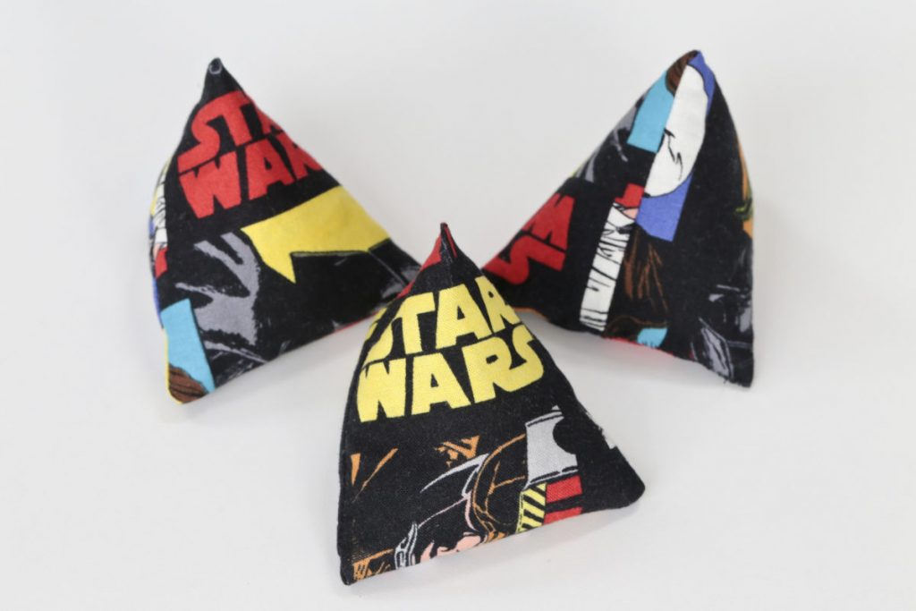 A set of three pyramid shaped juggling bags/sacks in black fabric with colourful Star Wars Logos and images