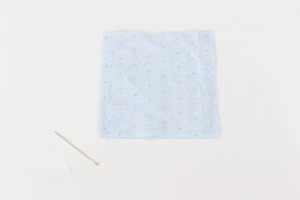With the two 10x10cm squares of blue spotted fabric right sides together, tack along one side.