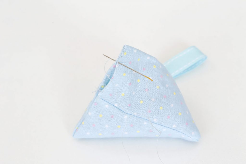 The pyramid lavender bag in blue material with spots is filled and the seam can now be hand stitched closed.