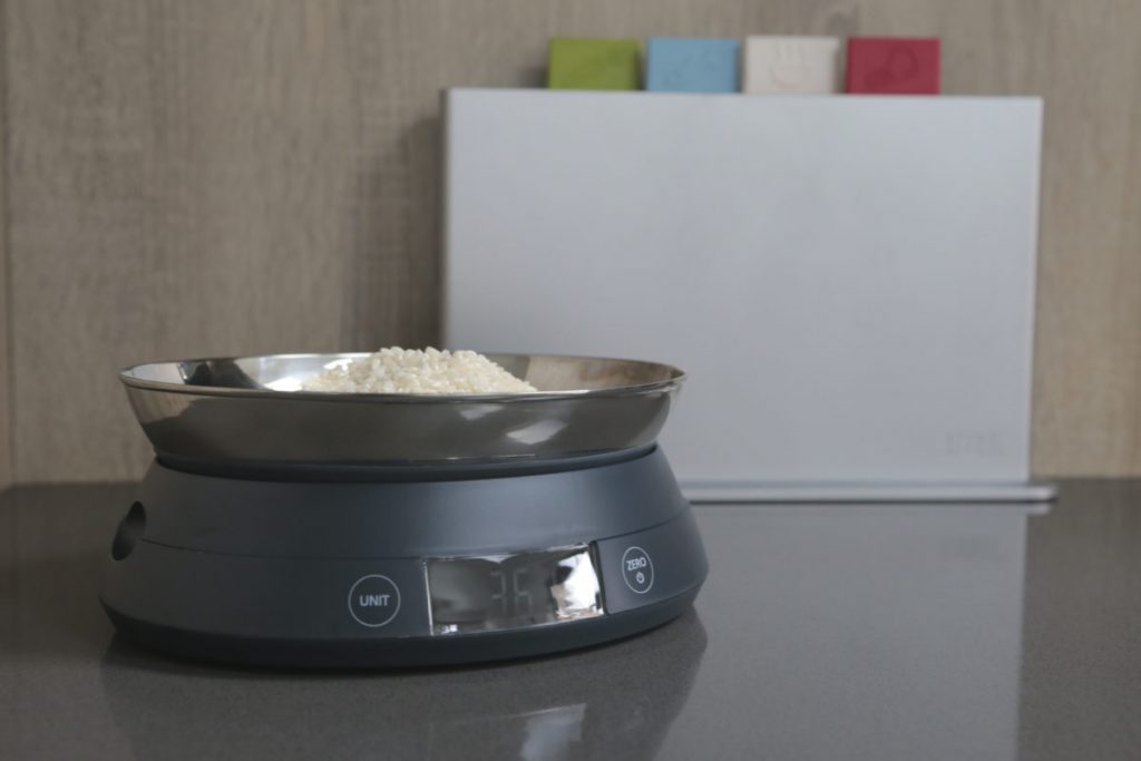 Joseph Joseph SwitchScale 2-in-1 Digital Scale with bowl facing upwards with uncooked rice in bowl with chopping board in the background