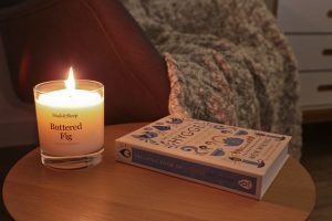 Close-up of candle alight on a side table with the Little Book of Hygge beside it