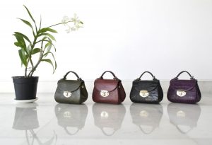 Four different coloured leather handbags in a row