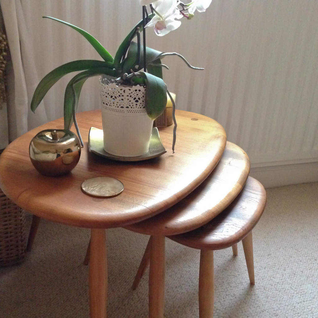 My mum's ercol pebble table nest in light wood with plant and gold ornaments on,