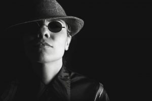 Black and white photo of a female spy with hat and dark glasses on
