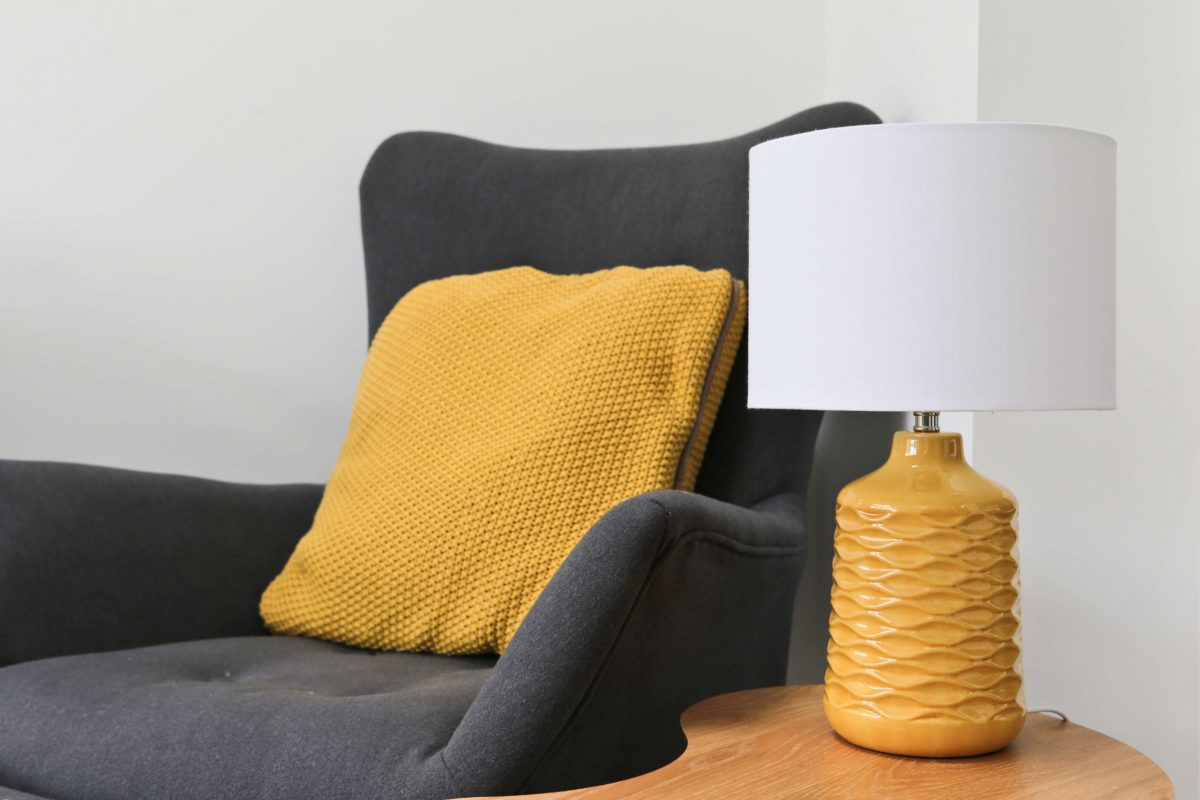 Mustard lamp, grey armchair and mustard cushion
